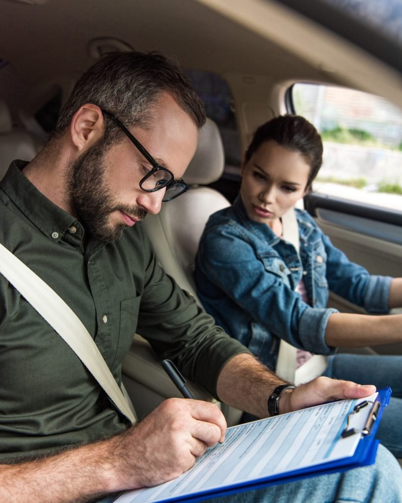 Driving instructor from A to Z Driving School reviewing a form with a learner driver in a car.